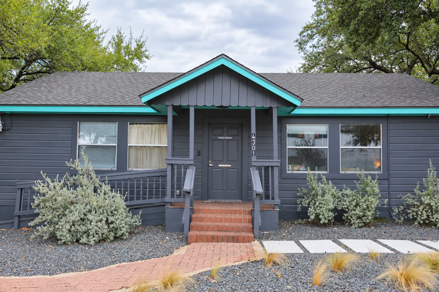 Front of Positive Pressure at 4301 Russell Drive, with charcoal siding, turquoise trim and a central porch.